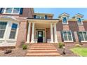 Close up of stately brick home's front entry, featuring columns and landscaped garden at 4541 Meadow Club Dr, Suwanee, GA 30024