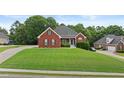 Brick home with a lush green lawn and an ample driveway offers great curb appeal at 9507 Greens Mill Ct, Loganville, GA 30052