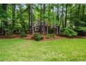 Landscaped front yard view featuring green grass, mature trees and shrubbery surrounding a beautiful house at 1772 Benningfield Sw Dr, Marietta, GA 30064