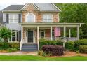 Inviting covered front porch with white columns and railing detail, plus manicured landscaping at 6610 Major Dr, Cumming, GA 30040