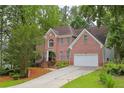 Beautiful brick residence featuring mature trees, lush greenery, and a convenient two-car attached garage at 7435 Woodruff Way, Stone Mountain, GA 30087