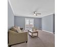 Cozy living room with neutral walls, carpet, ceiling fan, and a door leading to the outside at 122 Rue Fontaine, Lithonia, GA 30038