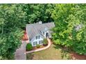 An aerial view shows this home nestled among mature trees with a rear deck at 2605 Woodland Hills Dr, Cumming, GA 30040