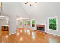A view of the living area with hardwood floors, fireplace, and windows overlooking lush greenery at 2605 Woodland Hills Dr, Cumming, GA 30040
