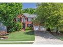 Attractive brick home with lush green lawn, mature trees, and an extended driveway leading to a two-car garage at 320 Ironhill Trce, Woodstock, GA 30189