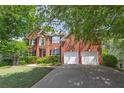 Beautiful brick home boasting a manicured lawn, black shutters, and a two-car garage, set against a backdrop of trees at 320 Ironhill Trce, Woodstock, GA 30189