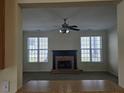 View of the spacious living room features a brick fireplace, two windows, and a ceiling fan at 4677 Liberty Square Dr, Acworth, GA 30101