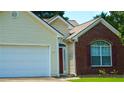 Close-up of home's exterior with brick accents, two-car garage and a red door at 965 Under Ct, Sugar Hill, GA 30518