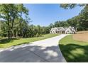 Long concrete driveway leading to a beautiful home surrounded by lush greenery at 779 Hicks Rd, Canton, GA 30115