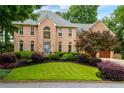 Elegant two-story brick home with a well-manicured lawn and mature landscaping at 2882 Clary Hill Ne Dr, Roswell, GA 30075