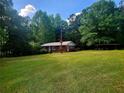 Well-maintained brick home boasts a spacious green lawn, mature trees, and storage shed for convenience at 309 Cornish Mountain Rd, Oxford, GA 30054