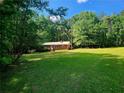 Charming brick home featuring a lush green lawn, mature trees, and a quaint storage shed at 309 Cornish Mountain Rd, Oxford, GA 30054