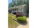 Charming gray home with landscaped yard, flowering shrubs, and a well-manicured lawn with a view of the driveway at 72 Victorian Cir, Dallas, GA 30157