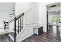 Bright entryway showcasing hardwood floors, staircase with black handrail, and a decorative bench at 870 Underhill Ct, Sugar Hill, GA 30518