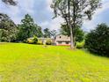 View of the split-level home surrounded by a spacious green lawn and mature trees at 792 Oneta Dr, Norcross, GA 30093