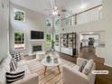 Bright living room with fireplace, tall windows, ceiling fan, and adjacent kitchen at 834 Winding Grove Ln, Loganville, GA 30052