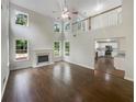 Bright living room with fireplace, tall windows, ceiling fan, and wood flooring at 834 Winding Grove Ln, Loganville, GA 30052