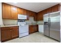 Well-lit kitchen boasts wooden cabinetry, a stainless refrigerator and white appliances at 115 Delmoor Nw Dr, Atlanta, GA 30311