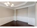 A dining room featuring elegant wainscoting, a modern chandelier, and dark hardwood floors at 139 Vinca Cir, Suwanee, GA 30024