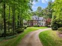 Stately brick home with circular drive surrounded by mature trees and manicured lawn at 530 Twinflower Ct, Roswell, GA 30075