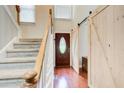 View of foyer with hardwood floors, staircase, and decorative sliding barn door at 1360 Stampmill Way, Lawrenceville, GA 30043