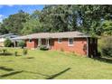 This is an exterior view of the brick home, with lawn, and mature trees on a sunny day at 3055 Henderson Mill Rd, Atlanta, GA 30341
