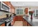 Kitchen featuring a stainless-steel stove, granite counters, wood cabinets and hardwood floors at 590 Kyle Trace Ct, Sugar Hill, GA 30518