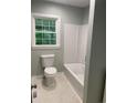 Bright bathroom featuring a white bathtub with shower and modern toilet at 2934 Union Grove Rd, Conyers, GA 30012