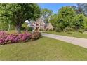 Beautiful brick home with a large front lawn, flowering bushes, and a concrete driveway at 1750 Providence Place Dr, Alpharetta, GA 30009