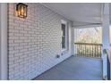 Cozy porch with whitewashed brick wall, stylish light fixture, and a glimpse of the natural outdoor scenery at 204 Elm St, Palmetto, GA 30268
