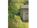 Side yard of the house with a pathway, lush greenery, and a view of the surrounding wooded area at 4287 Ridgetop Trl, Ellenwood, GA 30294