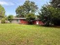 Expansive green backyard with a single-story home in the background featuring brick and red siding at 2857 Spanish Oak Sw Dr, Lilburn, GA 30047