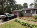 Exterior view of a brick house with an attached red garage and paved driveway; two cars are parked in the drive at 2857 Spanish Oak Sw Dr, Lilburn, GA 30047