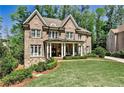 Beautiful brick home with meticulously maintained lawn and mature trees on a sunny day at 156 Lake Forrest Ne Ln, Atlanta, GA 30342