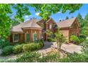 Stately brick home with lush landscaping, paver driveway, and mature trees providing shade and privacy at 5765 Riley Rd, Cumming, GA 30028
