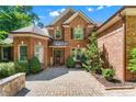 Charming brick home featuring a welcoming entrance with a paver walkway and manicured greenery at 5765 Riley Rd, Cumming, GA 30028