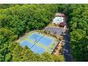 Aerial view of tennis courts and swimming pool surrounded by lush green trees at 1130 S Rudder Rd, Cumming, GA 30041