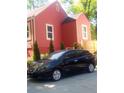Side view of a well-maintained red home with neat landscaping and a black vehicle parked nearby at 1105 Oak Knoll Ter, Atlanta, GA 30315