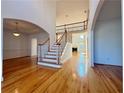 Spacious living room featuring gleaming hardwood floors, stairs, and fireplace at 6765 Crofton Dr, Alpharetta, GA 30005
