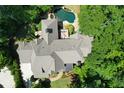 An aerial view reveals a custom home with a private backyard pool, lush landscaping, and expansive roof line at 1023 Little Darby Ln, Suwanee, GA 30024