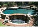 Resort-style pool featuring a rock waterfall, spa, and lush landscaping for a relaxing outdoor experience at 1023 Little Darby Ln, Suwanee, GA 30024