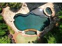 Aerial view of the luxurious backyard pool and spa surrounded by lush greenery and a stone patio at 1023 Little Darby Ln, Suwanee, GA 30024