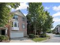 Brick townhome with attached garage surrounded by mature trees on a sunny day at 5159 Wellsley Bnd, Alpharetta, GA 30005