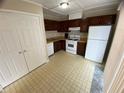 Kitchen featuring dark wood cabinets and white appliances next to a sliding glass door at 6448 Charter Way, Lithonia, GA 30058