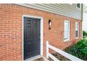 Close-up of the townhouse entrance with a brick facade, a dark door, and a well-lit porch area at 7750 Roswell Rd # 3D, Atlanta, GA 30350