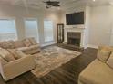 Bright living room featuring a cozy fireplace, dark wood floors, and plush sofas at 124 Archstone Sq, Mcdonough, GA 30253