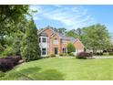 Charming brick home featuring an attached two-car garage, mature trees, and a lush green lawn at 106 Waterford Place Pl, Acworth, GA 30101