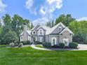 Stunning two-story home featuring a stone chimney, arched windows, and lush green landscaping at 237 Libby Ln, Canton, GA 30115