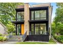 Contemporary two-story home boasting floor-to-ceiling windows, stone details, and lush greenery at 819 Belgrade Ne Ave, Atlanta, GA 30306