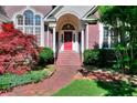 Welcoming front entrance with brick steps, red door, and decorative landscaping at 1595 Lake Lucerne Rd Sw, Lilburn, GA 30047